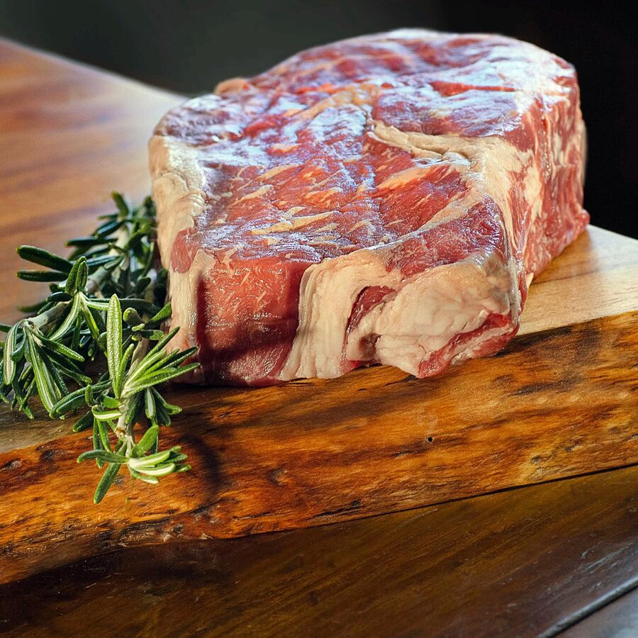 Raw ribeye on a board with rosemary